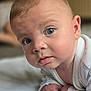 Wyatt is registered to the contest to win money with this photo: baby, blue_eyes, close_up, curious, face, infant, indoors, light_skin, looking_at_camera, person, portrait, soft_light, white_clothing, young_child, head, expression, crawling, skin, eyelashes, cheeks