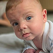 Wyatt is registered to the contest to win money with this photo: baby, blue_eyes, close_up, curious, face, infant, indoors, light_skin, looking_at_camera, person, portrait, soft_light, white_clothing, young_child, head, expression, crawling, skin, eyelashes, cheeks