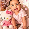 Kalina is registered to the contest to win money with this photo: baby, child, plush_toy, hello_kitty, pink_clothing, sitting, smiling, cute, indoor, soft_toy, hearts, text_overlay, pajamas, sock, toy, face, happy, childhood, adorable, portrait