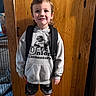 child, boy, young, smiling, portrait, standing, backpack, hoodie, school, student, elementary_school, wooden_door, indoor, home, clothing, shorts, shoes, face, full_body, photograph