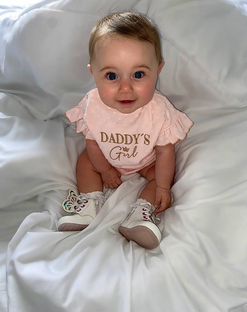Londyn is registered to the contest to win money with this photo: baby, baby_toddler_clothing, cheek, child, comfort, face, flash_photography, gesture, hairstyle, happy, iris, linens, person, pink, product, sitting, skin, sleeve, smile, textile