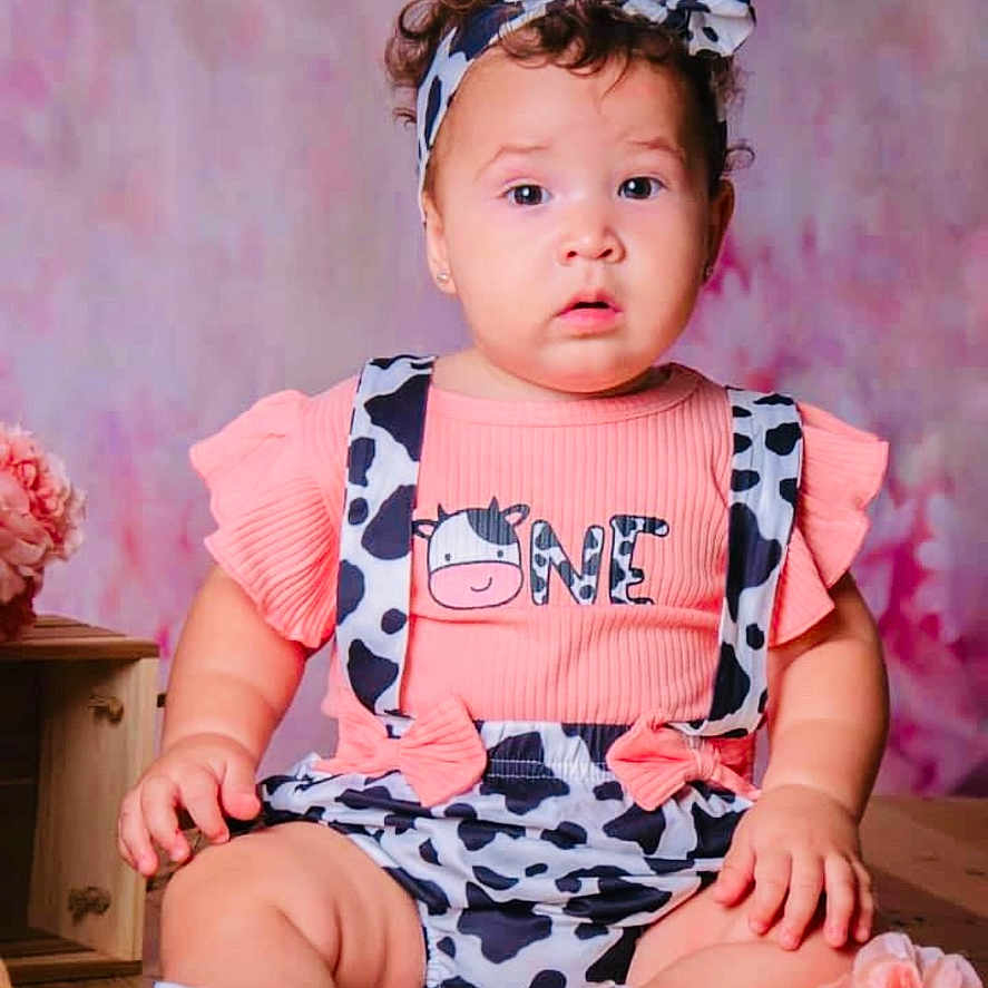 Meghan is registered to the contest to win money with this photo: adorable, baby, child, clothing, cow_print, curious, cute, expression, flowers, headband, indoors, infant, one_year, pink, portrait, shoes, sitting, soft_background, studio, wooden_floor