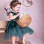 Meghan is registered to the contest to win money with this photo: toddler, girl, green_dress, tiara, basket, flowers, wooden_bench, curly_hair, smiling, indoor, carpet, decor, wreath, portrait, child, happy, cute, fashion, footwear, playful