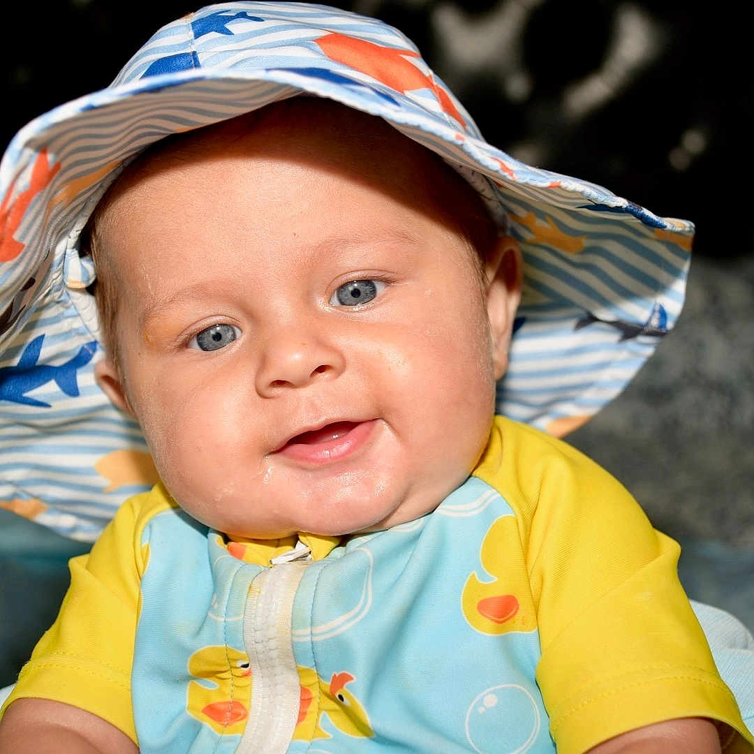 Bowie is registered to the contest to win money with this photo: apparel, baby, baby_girl, blue_eyes, child, chubby_cheeks, closeup, cute, face, happy, hat, headwear, indoor, infant, patterned_clothing, person, portrait, smiling, yellow_clothing, young_child