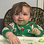 toddler, child, high_chair, pajamas, green_frosting, messy, face, hands, food, table, indoor, patterned_cushion, happy, blue_eyes, brown_hair, smile, celebration, holiday_theme, close_up, baby_food