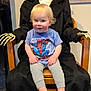child, toddler, skeleton, costume, spider_man, tshirt, chair, indoor, carpet, toy, hat, clothing, portrait, smiling, barefoot, person, black_coat, wooden_chair, decor, funny