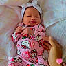Stormi is registered to the contest to win money with this photo: newborn, baby, infant, sleeping, portrait, pink_outfit, onesie, headband, bow, hello_kitty, bed, bedding, blanket, floral_pattern, adult_hand, wristband, heart_effects, indoors, cute, relaxed