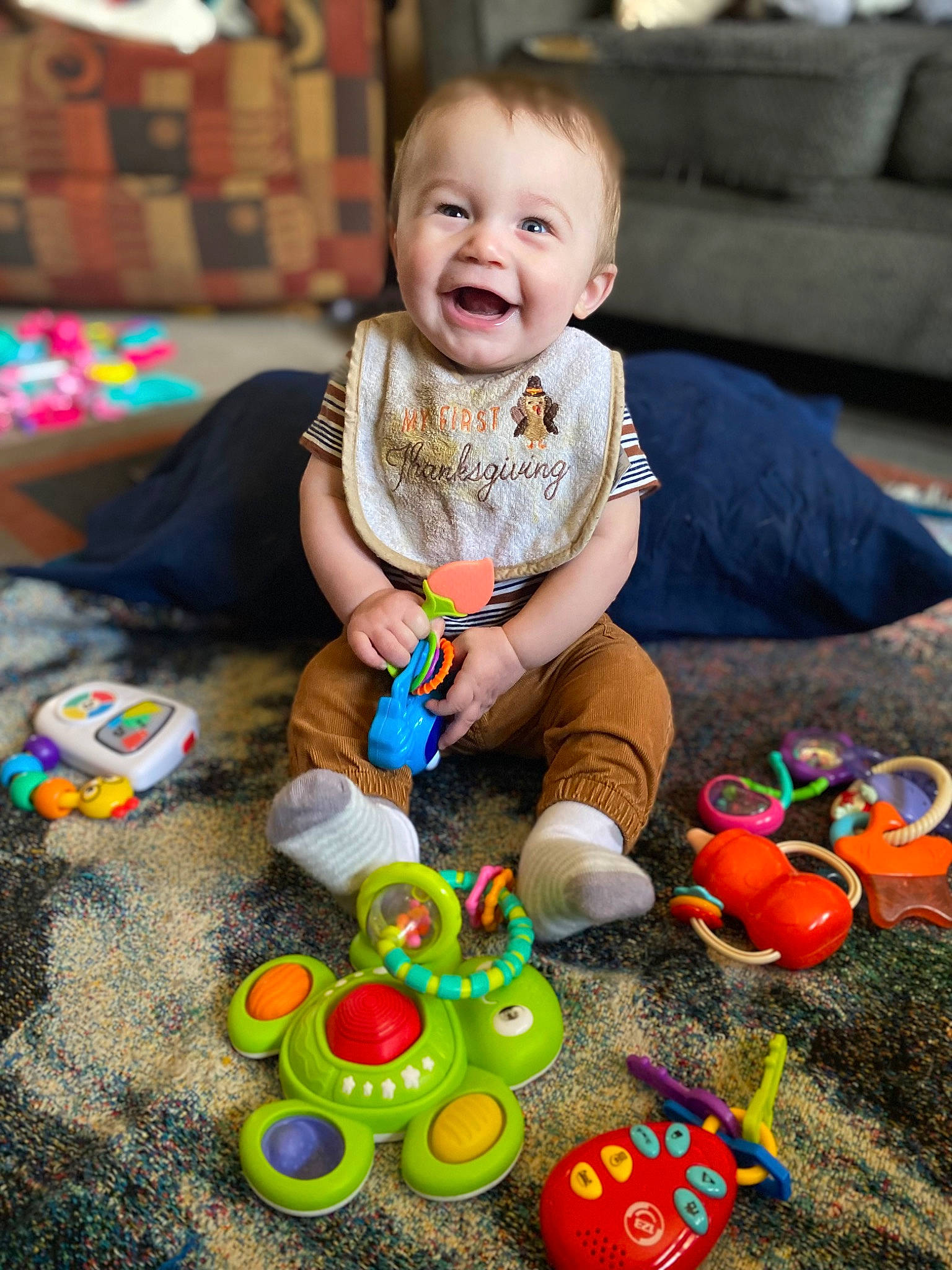 Lincoln is registered to the contest to win money with this photo: baby, baby_playing_with_toys, baby_toddler_clothing, child, couch, event, facial_expression, fun, green, happy, leisure, people, person, photograph, play, sitting, smile, snapshot, toddler, toy