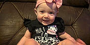 Novalee joined the competition — help win amazing prizes! apparel, baby, black_clothing, bow, brown_chair, child, cow_print, cute, feet, happy, headband, indoors, infant, leather_chair, person, playful, portrait, sitting, smiling, young_child