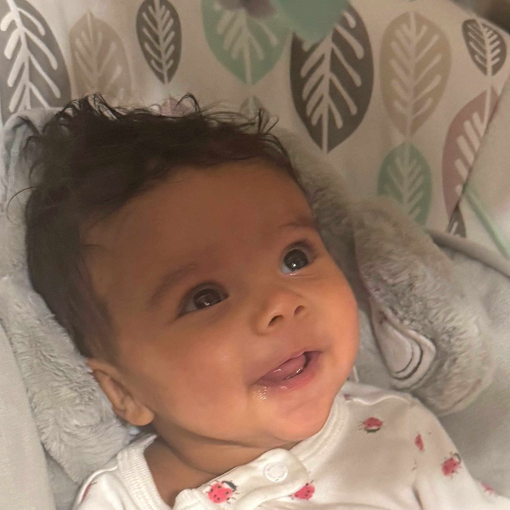 Eliana is registered to the contest to win money with this photo: baby, blanket, child, clothing, cozy, cute, expression, eyes, face, happy, head, indoor, infant, leaf, pattern, portrait, skin, smile, soft, young