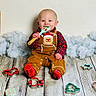 Walker is registered to the contest to win money with this photo: baby, child, infant, smiling, sitting, cookie_cutter, spatula, gingerbread, christmas, holiday, red_socks, plush_background, wooden_floor, festive_clothing, happy, indoors, cute, portrait, seasonal, playful