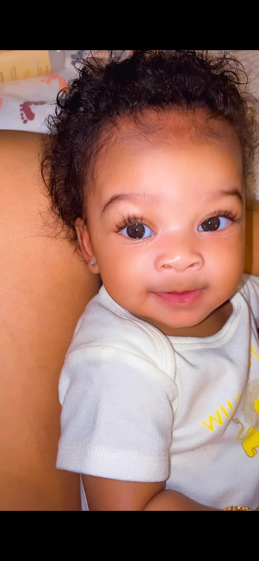 Malaya joined the competition — help win amazing prizes! baby, child, face, eyes, eyelashes, curly_hair, earring, white_shirt, lion_illustration, arm, skin, portrait, cute, infant, smile, closeup, person, indoor, young, childhood