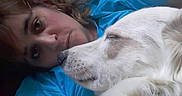 Yuna a rejoint le concours — aidez-le/la à gagner de superbes lots ! woman, person, dog, white_dog, pet, cuddling, lying_down, portrait, face, close_up, indoors, blue_shirt, white_fur, sleepy, affection, companion, black_background, photograph, date_caption, animals