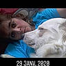 woman, person, dog, white_dog, pet, cuddling, lying_down, portrait, face, close_up, indoors, blue_shirt, white_fur, sleepy, affection, companion, black_background, photograph, date_caption, animals