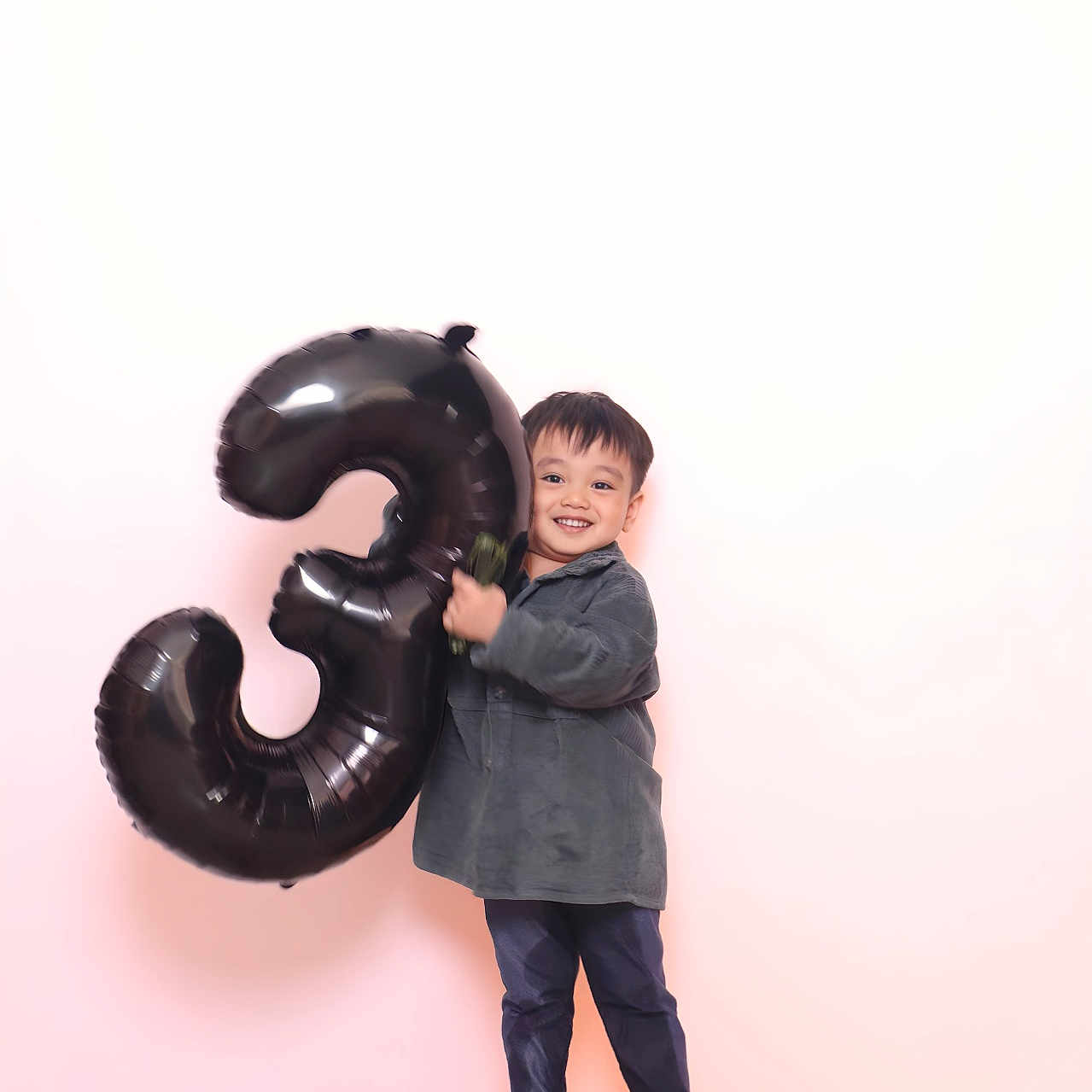 Marcus Jay is registered to the contest to win money with this photo: background, balloon, celebration, child, clothing, cute, fluffy_surface, footwear, fun, happy, holding, indoor, joy, number_three, party, portrait, smile, standing, toddler, young_child