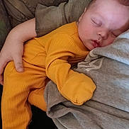 Liam is registered to the contest to win money with this photo: baby, sleeping, child, orange_clothing, person, arm, couch, cozy, indoor, comfort, peaceful, rest, human, infant, closeup, casual_clothing, napping, portrait, relaxation, soft_light
