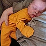 baby, sleeping, child, orange_clothing, person, arm, couch, cozy, indoor, comfort, peaceful, rest, human, infant, closeup, casual_clothing, napping, portrait, relaxation, soft_light