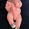 Eliana joined the competition — help win amazing prizes! baby, child, infant, portrait, smiling, happy, lying_down, pink_outfit, onesie, baby_socks, dark_blanket, quilt, indoor, closeup, face, hands, feet, animal_pattern, cute, photography