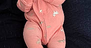 Eliana is registered to the contest to win money with this photo: baby, infant, child, portrait, lying_down, smiling, happy, pink_onesie, clothing, slippers, dark_blanket, quilt, bed, indoor, cozy, cute, face, hands, self_soothing, photography