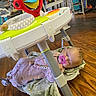 baby, sleeping, pacifier, blanket, baby_activity_center, wooden_floor, toys, pink, clothing, indoor, child, cute, onesie, infant, floor, store, relaxing, peaceful, face, head