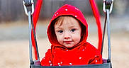 Phoebe joined the competition — help win amazing prizes! baby, child, clothing, cute, daylight, face, fall, fun, leaves, nature, outdoor, park, person, playground, red_hoodie, seat, smiling, swing, toddler, young
