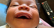 Jahmaika joined the competition — help win amazing prizes! baby, child, closeup, clothing, couch, expression, face, hair, happy, head, infant, joy, living_room, mouth, person, remote_control, skin, smile, teeth, white_outfit