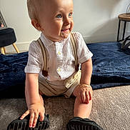Reuben is registered to the contest to win money with this photo: toddler, child, smiling, indoor, carpet, blue_eyes, shorts, shirt, suspenders, shoes, happy, sitting, bracelet, light, person, cute, baby, young_child, home, portrait