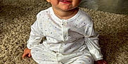 Reuben is registered to the contest to win money with this photo: baby, child, pajamas, polka_dot, carpet, floor, indoor, smile, sitting, face, blue_eyes, hand, footed_pajamas, hair, cute, infant, home, light, expression, person