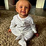 baby, child, pajamas, polka_dot, carpet, floor, indoor, smile, sitting, face, blue_eyes, hand, footed_pajamas, hair, cute, infant, home, light, expression, person