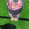 baby, swing, pacifier, pink_clothing, hoodie, hat, blanket, fuzzy_slippers, playground, green_surface, child, outdoor, sunlight, cute, infant, seat, toy, soft_toys, person, playtime