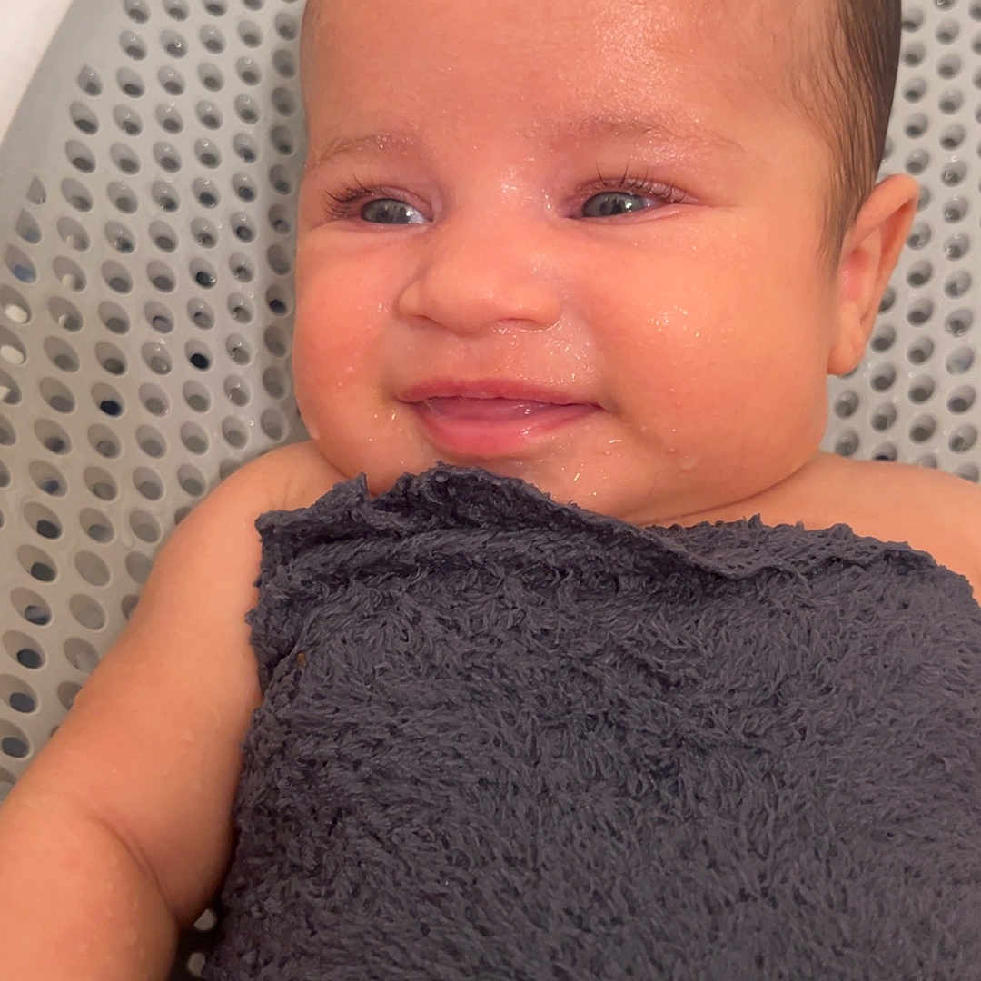 Jaelani is registered to the contest to win money with this photo: arm, baby, background, blue_eyes, child, closeup, expression, face, happy, head, indoors, infant, newborn, person, portrait, skin, smiling, towel, water_drops, wet_skin