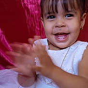 Alejandra joined the competition — help win amazing prizes! child, toddler, girl, smiling, happy, clapping, portrait, white_dress, blue_bow, hair_bow, long_hair, fringe, indoors, pink_background, celebration, motion_blur, jewelry, necklace, seated, photography