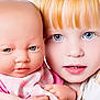 child, doll, baby_doll, red_hair, blue_eyes, face, portrait, close_up, toy, playtime, pink_clothing, human, realistic_doll, innocence, curiosity, childhood, cute, expression, holding, young