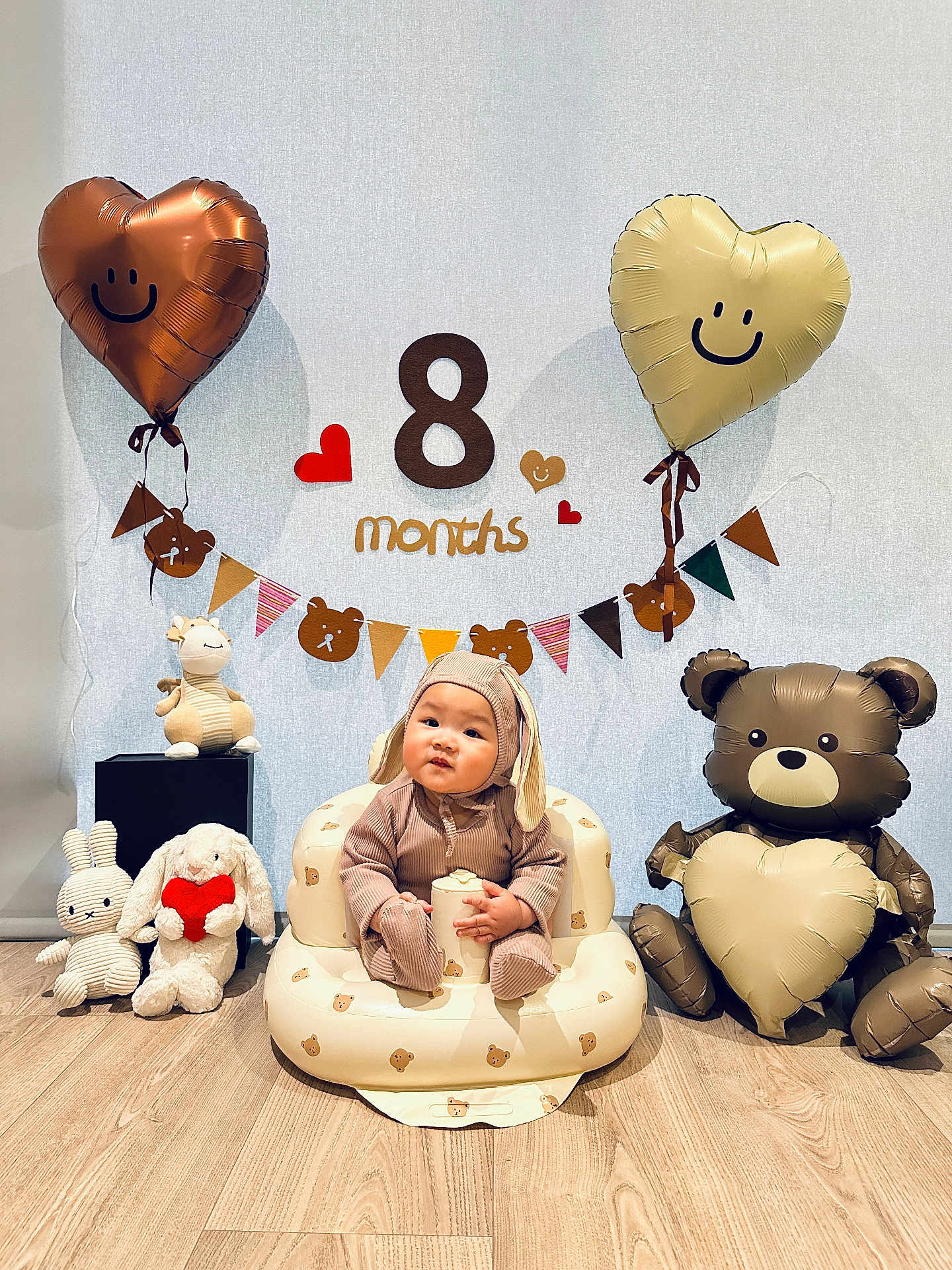 Desmond joined the competition — help win amazing prizes! baby, infant, bunny_outfit, plush_toys, inflatable_chair, balloons, heart_balloon, bear_balloon, wooden_floor, banner, milestone, smile, cute, celebration, indoor, child, toy, decorations, happy, person