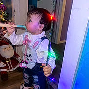 Layla joined the competition — help win amazing prizes! toddler, child, indoor, christmas_lights, holiday, toy, bunny_bib, jeans, ripped_jeans, whisk, face, person, floor, wooden_floor, santa_doll, decorations, colorful_lights, curious, standing, holiday_season