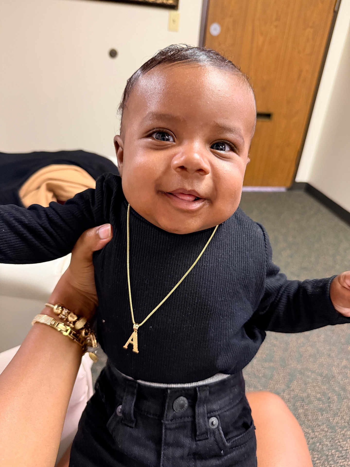 Airess is registered to the contest to win money with this photo: baby, child, smiling, portrait, indoor, necklace, black_clothing, hand, person, face, cute, happy, jewelry, carpet, door, furniture, holding, skin, expression, young