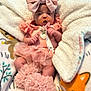 baby, infant, pink_clothing, headband, bow, pacifier, blanket, ruffles, soft_toys, cute, cozy, sleepwear, child, newborn, tutu, plush, comfort, indoors, resting, adorable