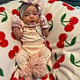 Amyra is registered to the contest to win money with this photo: baby, infant, pacifier, headband, mittens, blanket, cherry_pattern, pink_clothing, sleepy, cute, soft_texture, lying_down, newborn, adorable, cozy, toddler, fabric, child, indoor, portrait
