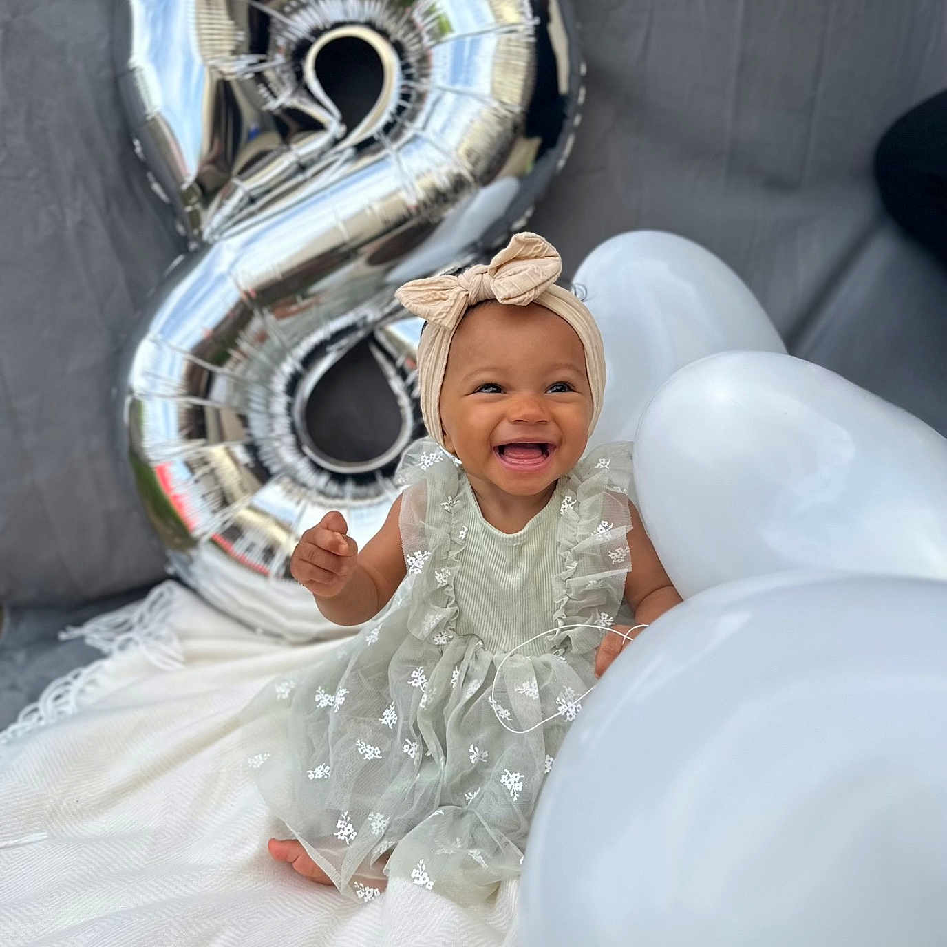 Jïa a rejoint le concours — aidez-le/la à gagner de superbes lots ! baby, balloon, birthday, blanket, celebration, child, cute, dress, festive, happy, headband, infant, number_balloon, outdoor, person, portrait, silver_balloon, sitting, smiling, white_balloon