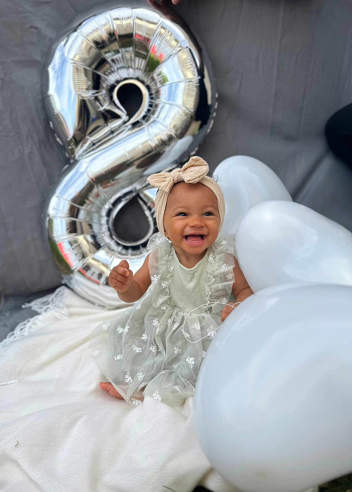 Jïa a rejoint le concours — aidez-le/la à gagner de superbes lots ! baby, child, smiling, dress, headband, balloon, number_balloon, silver_balloon, white_balloon, blanket, celebration, birthday, happy, sitting, cute, portrait, outdoor, person, festive, infant