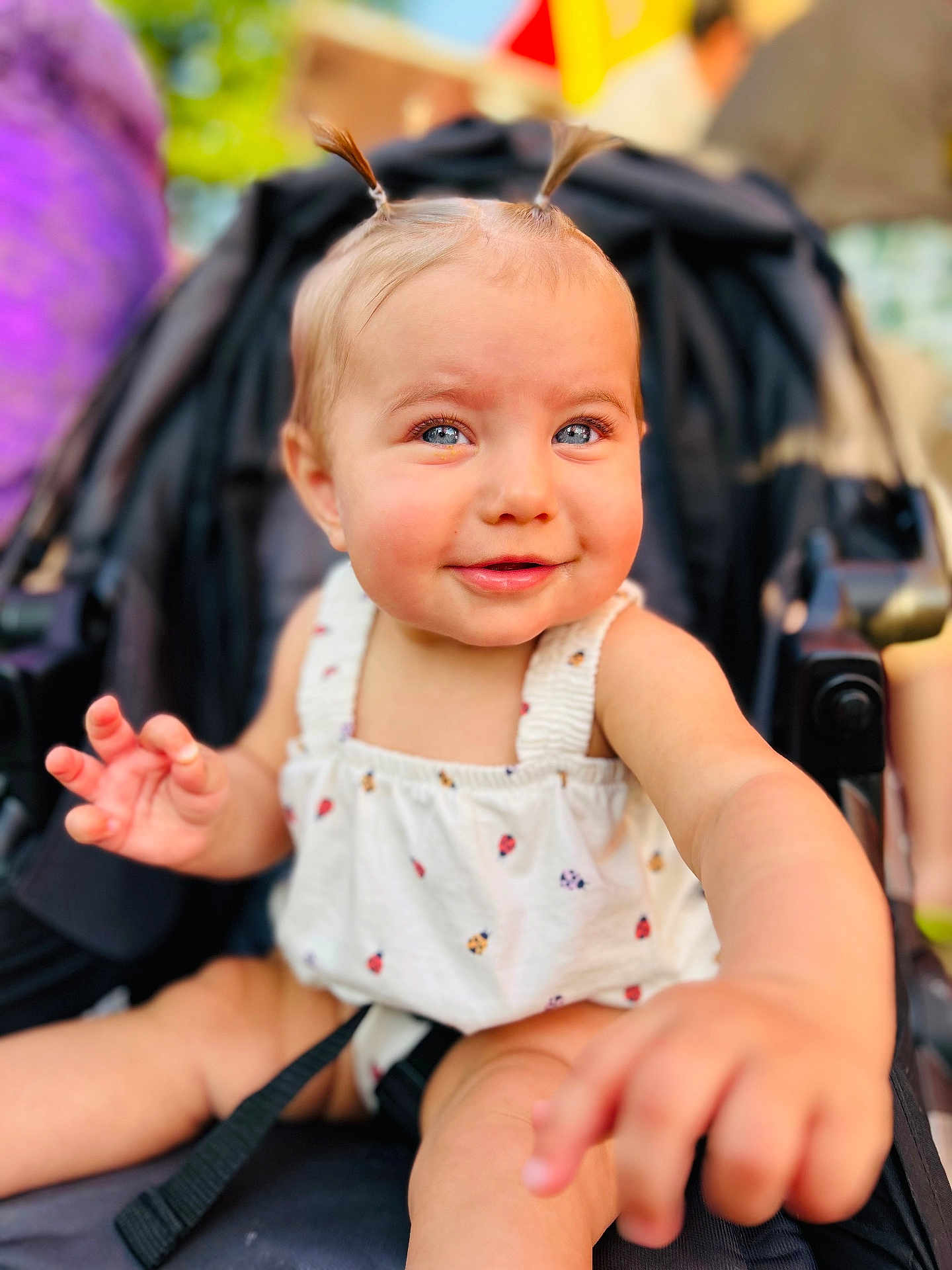 Merrin joined the competition — help win amazing prizes! baby, child, stroller, pigtails, smiling, outdoor, cute, infant, person, happy, skin, clothing, reaching, face, portrait, seatbelt, summer, daylight, expression, closeup