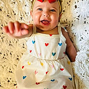 Merrin joined the competition — help win amazing prizes! baby, child, smiling, red_bow, dress, hearts, hand, happy, cute, portrait, face, blue_eyes, blanket, texture, indoor, infant, closeup, person, sitting, white