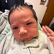 Benito joined the competition — help win amazing prizes! baby, infant, face, expression, furrowed_brow, onesie, hand, manicure, indoor, door, wall_decor, curly_hair, person, portrait, close_up, cozy, blanket, furniture, skin, clothing