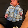baby, infant, plaid_shirt, blue_shirt, black_pants, white_socks, lying_down, curious_expression, indoor, person, child, human, skin, face, hand, legs, casual_clothing, portrait, newborn, relaxed