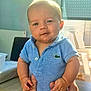 baby, child, infant, blue_clothing, polo_shirt, smiling, drool, hands, indoor, sunlight, face, portrait, cute, chubby, holding, table, person, short_hair, happy, skin