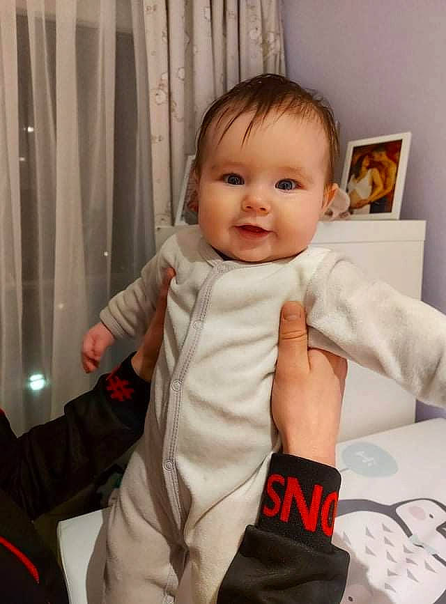 Hélèna participe au concours pour gagner de l'argent avec cette photo : baby, baby_toddler_clothing, cheek, comfort, curtain, eye, facial_expression, finger, gesture, hair, happy, joint, person, picture_frame, shoulder, skin, sleeve, smile, standing, thumb