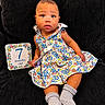 baby, child, 7_months_old, blue_eyes, floral_dress, socks, couch, milestone_card, indoor, portrait, cute, infant, sitting, clothing, person, face, head, expression, comfort, colorful