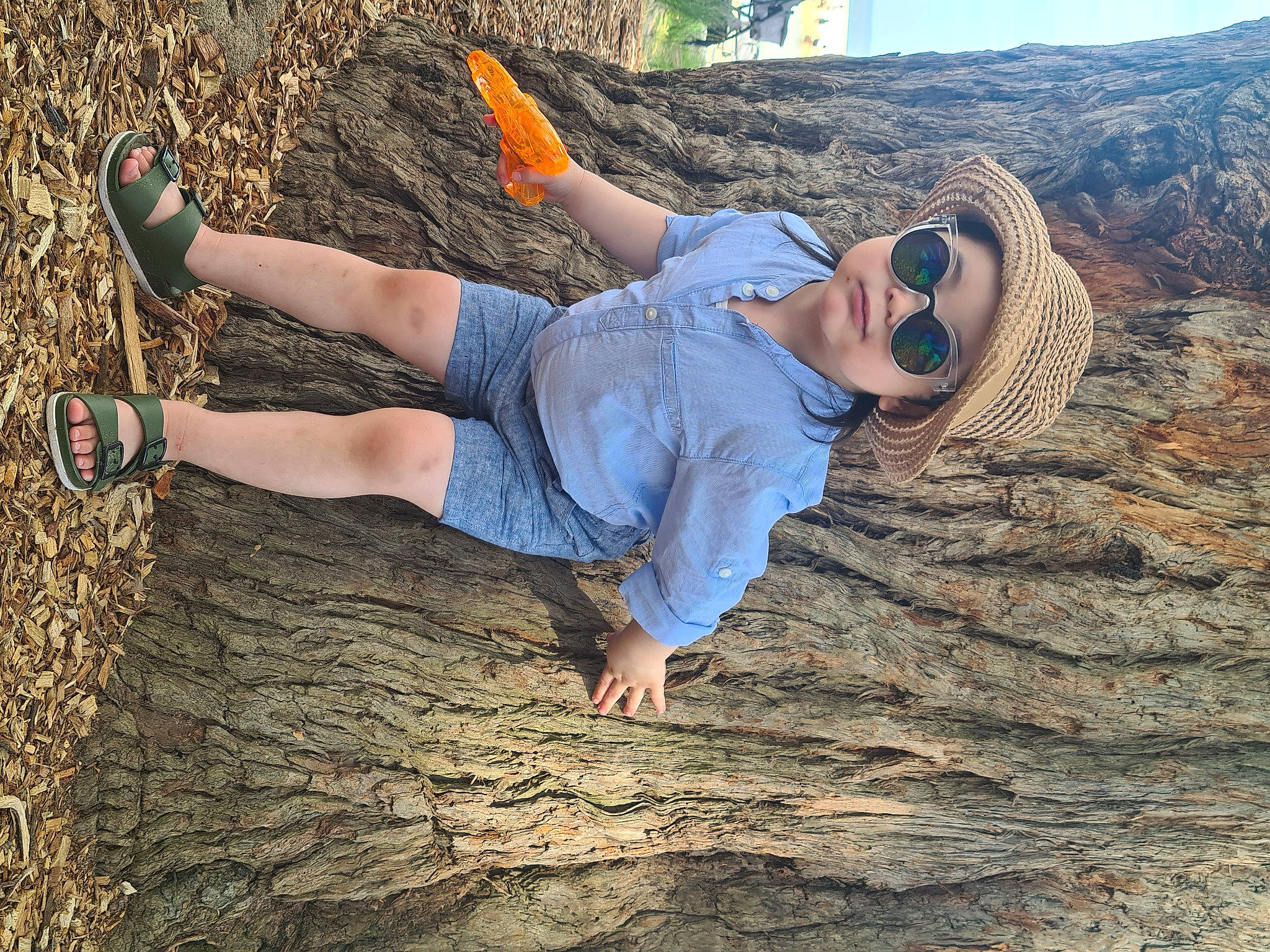 Cayden is registered to the contest to win money with this photo: bedrock, cool, goggles, grass, happy, headwear, knee, landscape, leg, leisure, nature, people_in_nature, person, plant, shoe, shorts, sneakers, sunglasses, thigh, tree