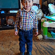 Israel joined the competition — help win amazing prizes! child, boy, plaid_shirt, blue_jeans, boots, indoor, floor, wood_paneling, television, furniture, baby_toy, smile, standing, young, casual_clothing, home, cozy, cluttered, person, portrait