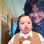 Rene joined the competition — help win amazing prizes! toddler, child, adult, face, smile, bow_tie, vest, indoor, wooden_wall, hair, expression, clothing, person, portrait, funny_face, dirt, closeup, happy, casual, family